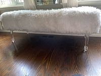 Front view of full bench showing white faux fur upholstery and clear acrylic legs
