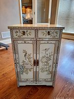 Front exterior showing two top drawers, double doors with metal handles, hand-painted floral and bird design