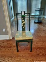 Front view of the wood chair showing the seat cushion and painted backrest