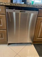 Front view showing stainless steel dishwasher installed under granite countertop