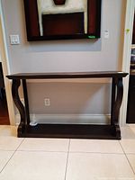 Front view of the wood hallway table showing the rectangular top, curved side supports, and bottom shelf.