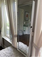 Full view of cabinet showing mirrored door and white textured sides in room setting