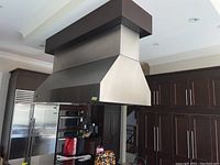 Full view of stainless steel wall-mounted chimney hood installed in kitchen under soffit