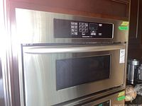 Front view of built-in stainless steel microwave installed in wood cabinetry