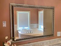 Full front view of the mirror showing size, frame, and reflection detail in the room with windows and bathtub.