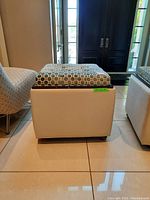 Side view of ottoman with fabric top cushion showing vinyl base and wheels