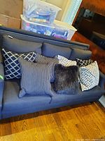 View of all seven side pillows arranged on a blue couch showing various patterns and textures.