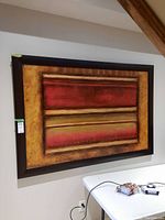Frontal view of the abstract print showing the full artwork and wooden frame on a wall above a white table.
