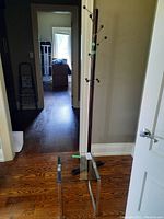 Wooden coat rack and metal base side table with glass top in a hallway