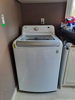Full front view of white top-load washer in laundry space