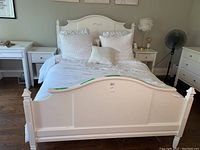 Full view of assembled white bed frame with comforter and pillows