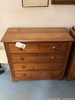 Front view of wooden 4 drawer pine dresser showing natural wood color and round knob handles on each drawer