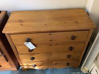 Front view of a pine dresser with four drawers, each with two round wooden knobs, and some visible keyholes on drawers.
