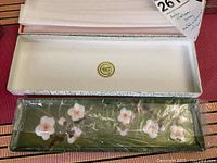 Open box with cloisonné tray showing floral design inside, rectangular shape, dark green enamel, and white/pink flowers.