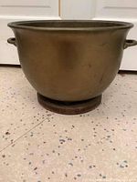 Brass cauldron front view showing rounded body and handles