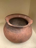 Full view of the round-bodied reddish-brown clay pot with wide rim