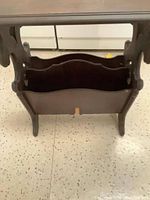 View of the magazine rack under the side table showing its capacity and scalloped edges on sides.
