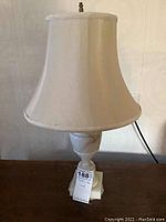 Marble table lamp with cream shade pictured against a beige wall, showing the lamp off position.