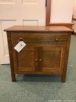 Front view of oak side table showing drawer and cabinet doors closed.