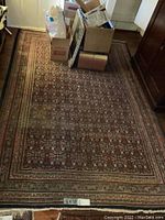 Full view of the oriental rug placed on floor with boxes nearby to indicate size and condition.