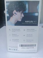 Photo of Haylou W1 earbuds packaging showing key features: stunning sound quality, Bluetooth 5.2, Qualcomm QCC3040 chip, 20-hour battery life, 4-mic clear calls, smart touch control.