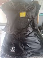 Full view of Ptahdus heated vest showing front zipper, logo, and two side pockets.