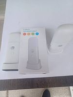 Two white LED night lights alongside their retail box. Each night light is cylindrical with a motion sensor and button on the front.