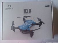 Top of box showing brand Deerc, model D20, HD camera, suitable for ages 14+. Image shows the drone and model name on the box.