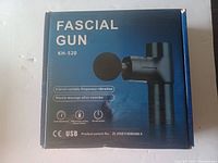Box of the Fascial Gun KH-520 showing product image and features like 4-level vibration, USB charging, muscle massage for after exercise.