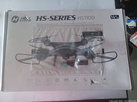 Front of the HolyStone HS-Series HS110D drone box showing image of the drone, brand logo, series, and model name. The box has visible damage.
