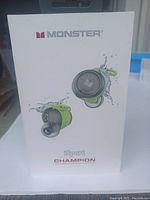 Front of box showing Monster brand and image of lime green sport earbuds with charging case.