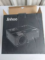 Black Jinhoo projector box with white line art image of the projector on front and brand name on top left corner.