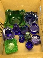 Top-down photo showing most glass items arranged in a box, various blue and green glass bowls and bottles visible.