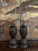 Full front view of both bronze lamps showing shape, patina, harps, cords