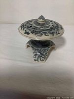 Side view of blue and white ceramic incense burner showing dragon motifs and arched feet base