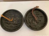 Obverse view of both bronze discs showing raised relief motifs and braided cords