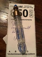 Full view of crystal snuff bottle showing blue and clear cut crystal design with brass cap and blue pointed finial.