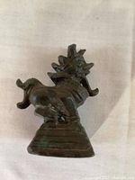 Side view of small heavy metal Foo Dog statue showing detailed lion dog figure and posture on stepped base