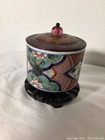 Photo showing the ceramic cup with wooden lid and wooden stand together from a side view.