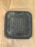 Top view of the square metal tray showcasing raised Kanji lettering across the center.