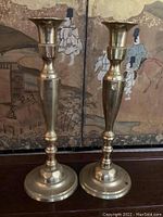 Two brass candle holders side by side showing full height and design details.