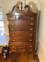 Front view of the vintage Chippendale style high boy showing detailed drawers, brass handles, and top finial.