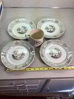 Four brown transferware plates arranged around a cup on a countertop with measuring tape to show size.