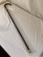 Full view of the wooden cane with curved hook handle lying on white fabric background.