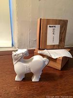 Side view of one white horse figurine with wooden box behind it, showing label 'HORSE' and Japanese text.