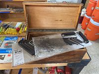 Wooden toolbox with lid open showing Allen wrenches inside, some still wrapped in plastic