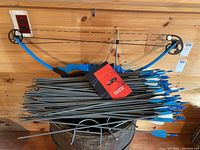 Full view of blue Genesis compound bow alongside a large bundle of arrows with blue fletching.