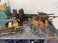 Overall shot of assorted metal and wooden clamps, showing different types and sizes on a table.