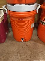 Photo of orange Rubbermaid drink dispenser with white handles and base spigot.