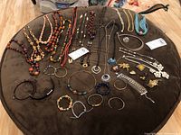 Full view of all jewelry items including beads, chains, pins, and bracelets spread out on a brown surface